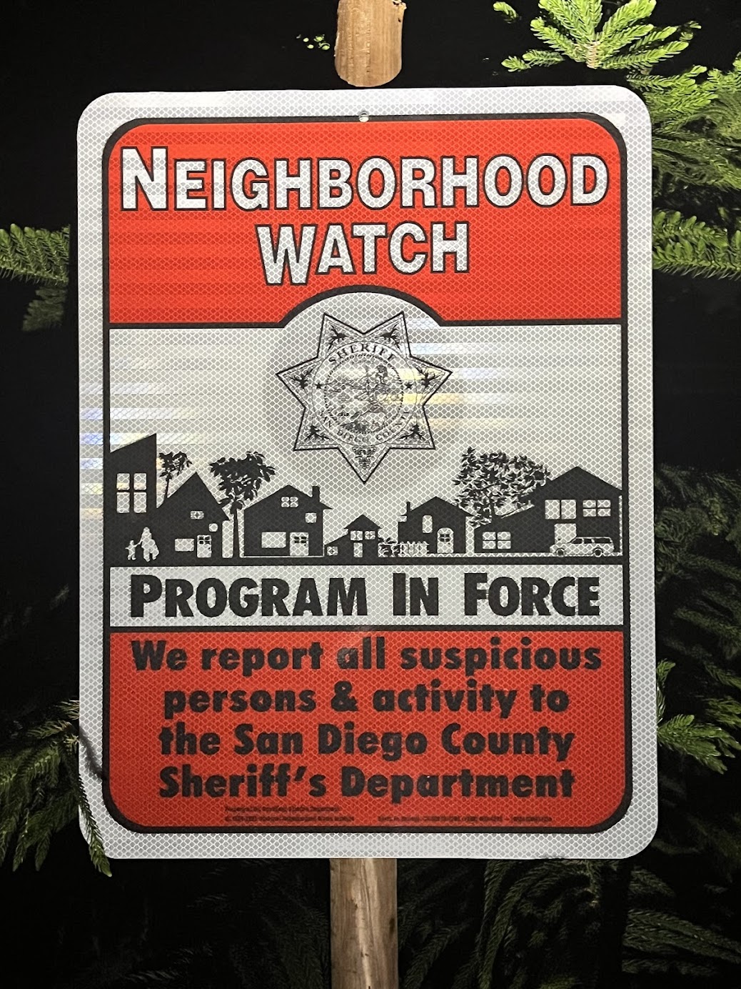 Reflective neighborhood watch sign at night, reflective surface visibly glowing